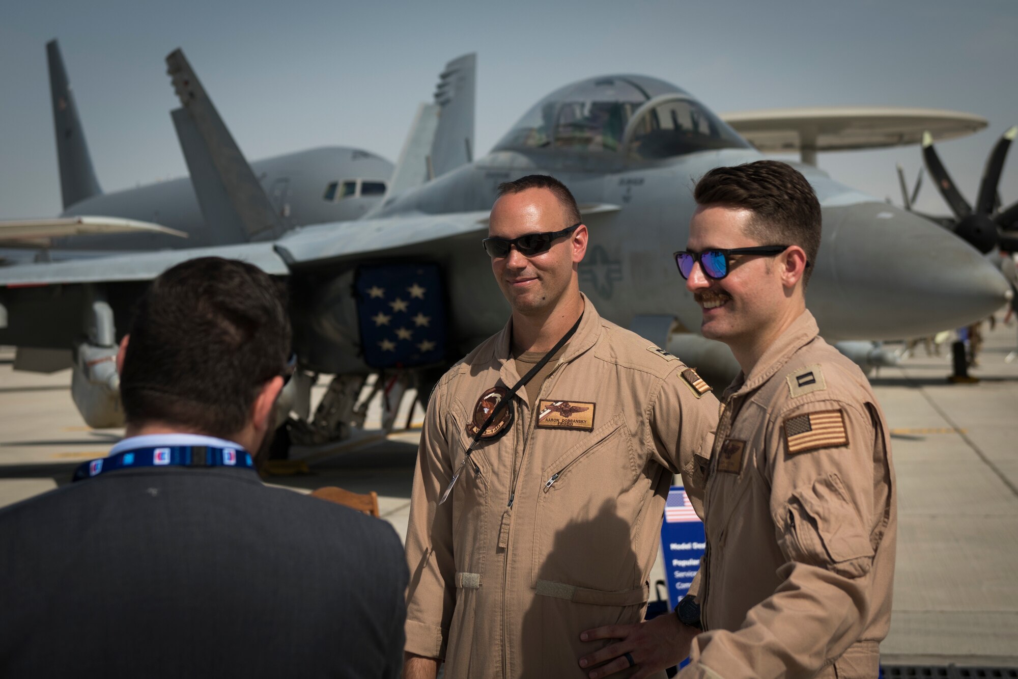 U.S. Navy Lts. Aaron Dobransky, center, a pilot with the "Patriots" of Electronic Attack Squadron (VAQ) 140, and Chris Czapski, right, an electronic warfare officer with the VAQ-140, converse with a spectator at the Dubai Airshow, United Arab Emirates, Nov. 17, 2019.