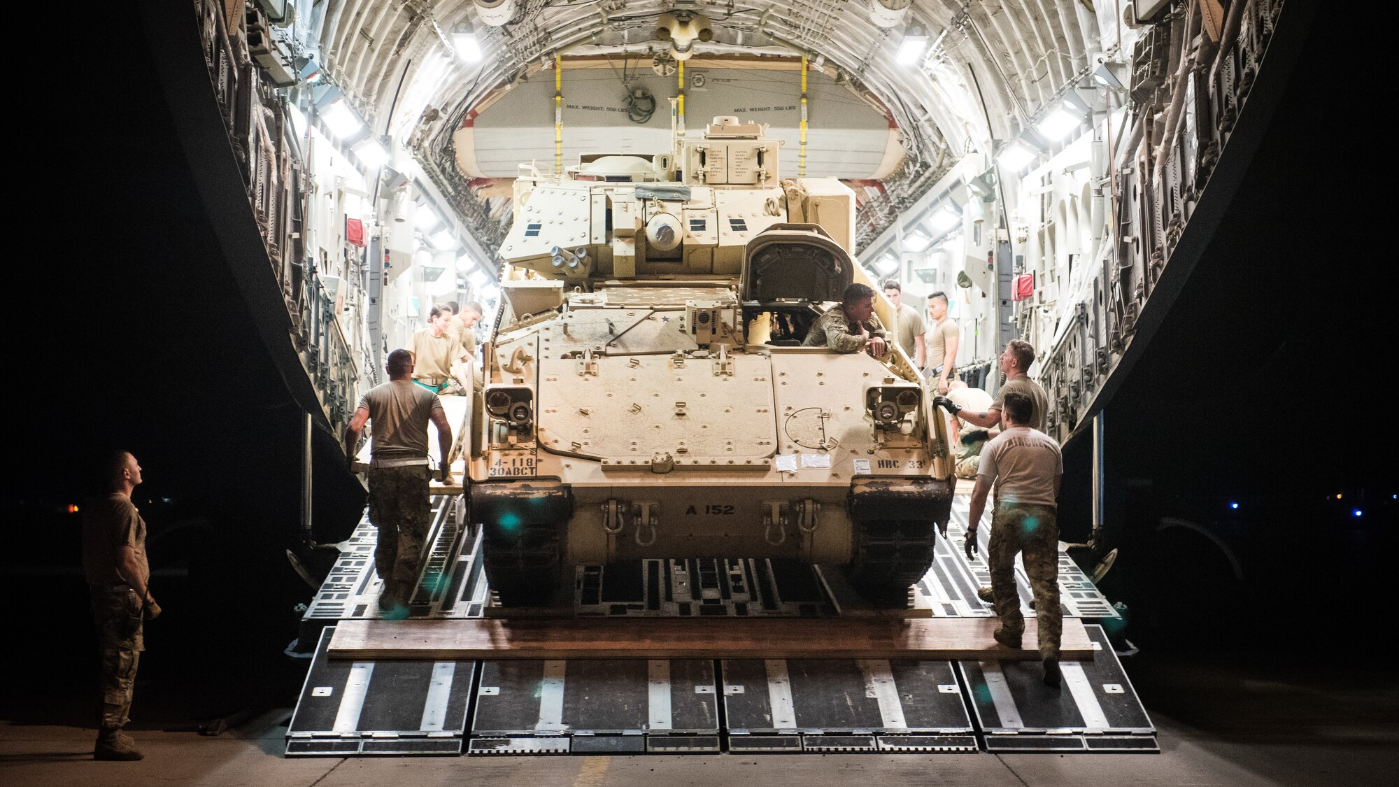 U.S. Airmen assigned to the 386th Expeditionary Logistics Readiness Squadron talk with a U.S. Army Soldier driving a U.S. Army M2 Bradley Fighting Vehicle onto a U.S. Air Force C-17 Globemaster III at Ali Al Salem Air Base, Kuwait, Oct. 30, 2019. Airmen and Soldiers coordinated efforts to transport the BFV within the U.S. Central Command theater of operations to assist in ongoing efforts within the region. (U.S. Air Force photo by Capt. Thomas Barger)