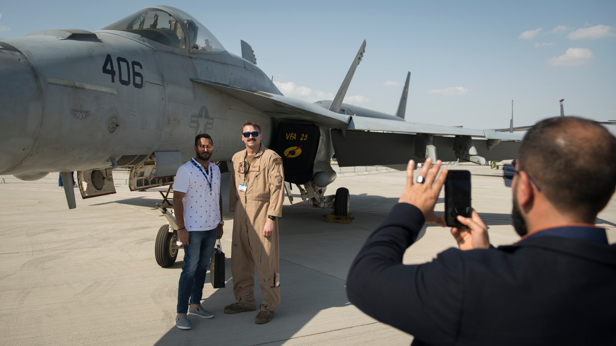 U.S. Navy Lt. Nate Noel, right, an MH-60R Sea Hawk pilot with the "Griffins" of Helicopter Maritime Strike Squadron (HSM) 79, poses for a photograph with a spectator at the Dubai Airshow, United Arab Emirates, Nov. 18, 2019.