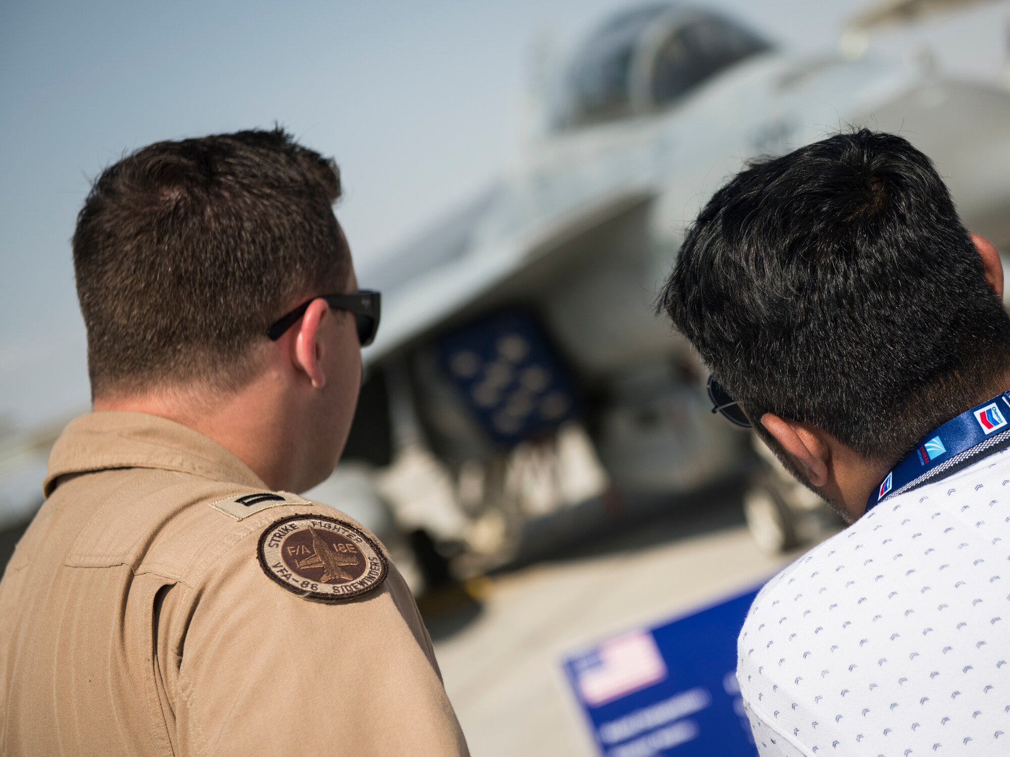 U.S. Navy Lt. Blake Rademaker, left, an F/A-18E Super Hornet pilot with the "Sidewinders" of Strike Fighter Squadron (VFA) 86, discusses U.S. Navy EA-18G Growler capabilities at the Dubai Airshow, United Arab Emirates, Nov. 18, 2019.