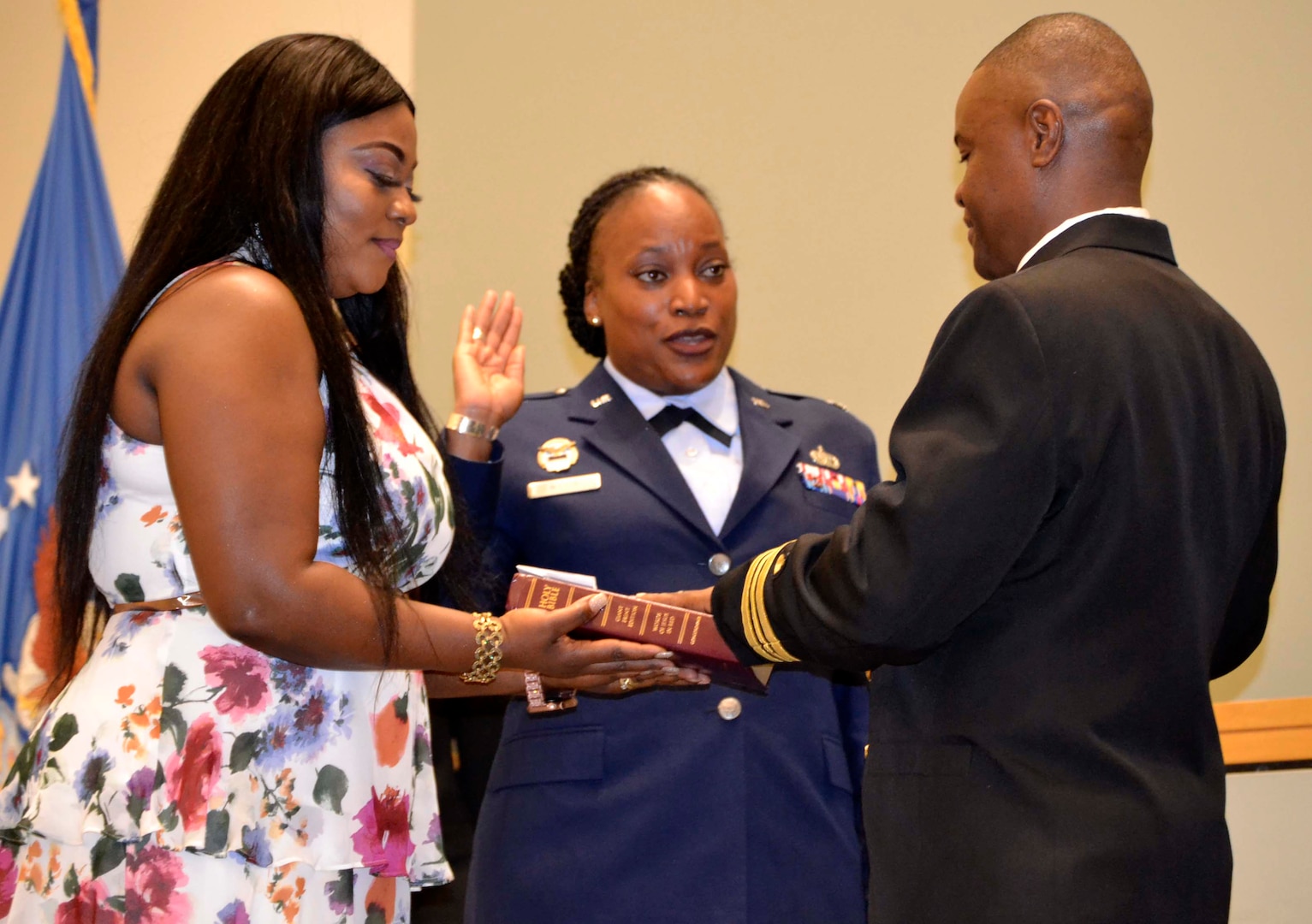 Naomi Tailey, left, wife of Navy Lt. Cmdr. Prince Tailey, right, stands beside Air Force Lt. Col. Chiriga Wilson, center, holding the Bible on which her husband reaffirms his oath of service during a promotion ceremony in his honor November 22, 2019, in Philadelphia.