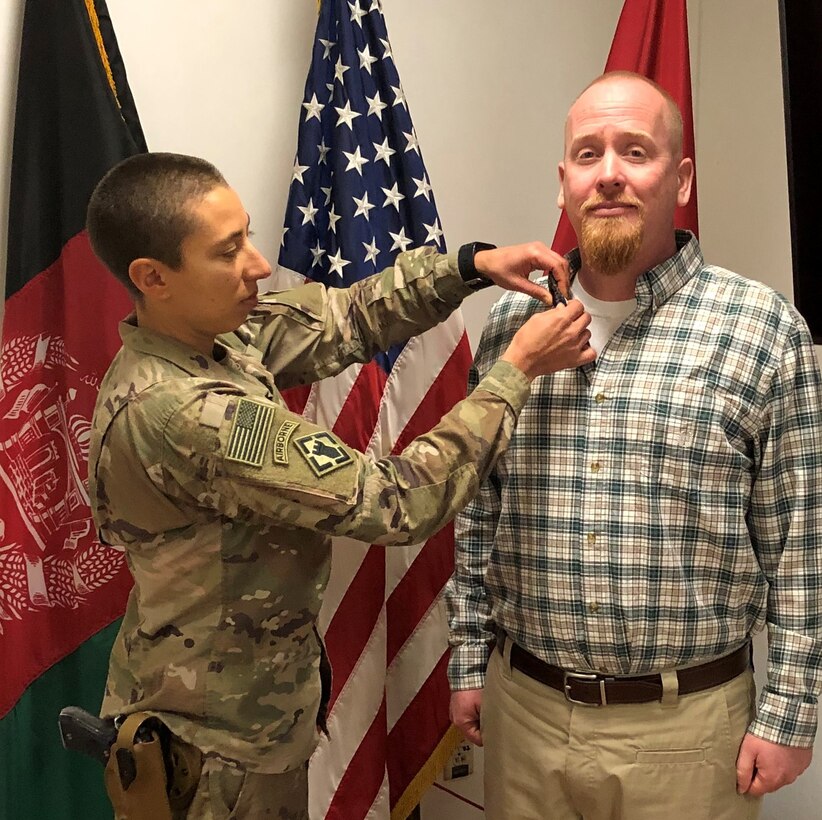MAJ Maria Carver pins the Civilian Service Achievement Medal on the collar of David Hardin during an impromptu award ceremony at the Kabul Cluster.