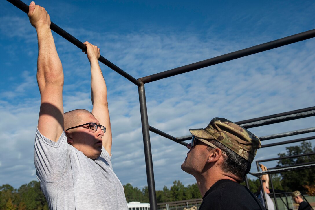 A photo of an Air Force Ranger Assessment Course cadre evaluating a student