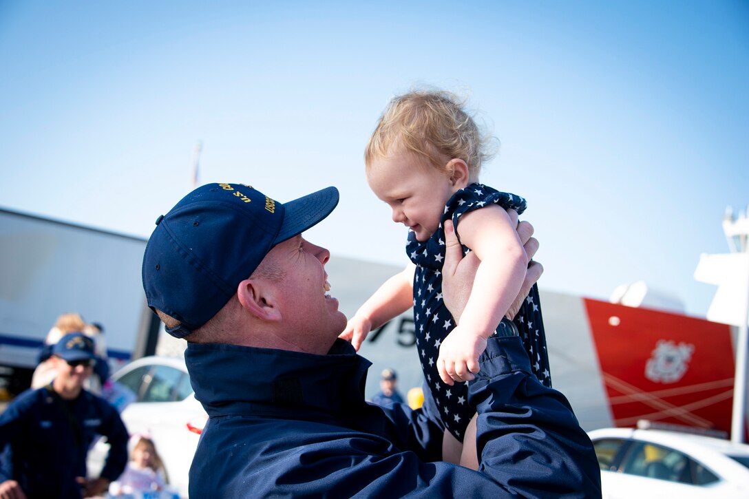 A Coast Guardsman holds up a baby.