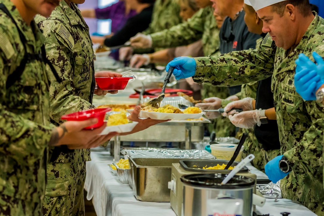 Service members stand in line to get served during a Thanksgiving dinner.