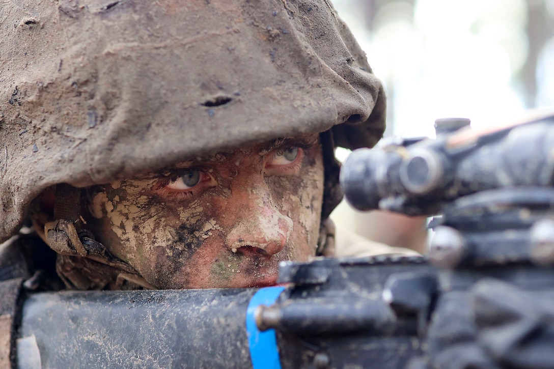 A Marine Corps recruit looks through a view finder on a weapon.