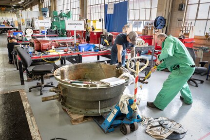 Emil Skarpova, right, a Shop 31, Inside Machine Shop bench mechanic, works with teammates to repair a check valve in the newly remodeled Work Center-402 floor space inside Building 431.