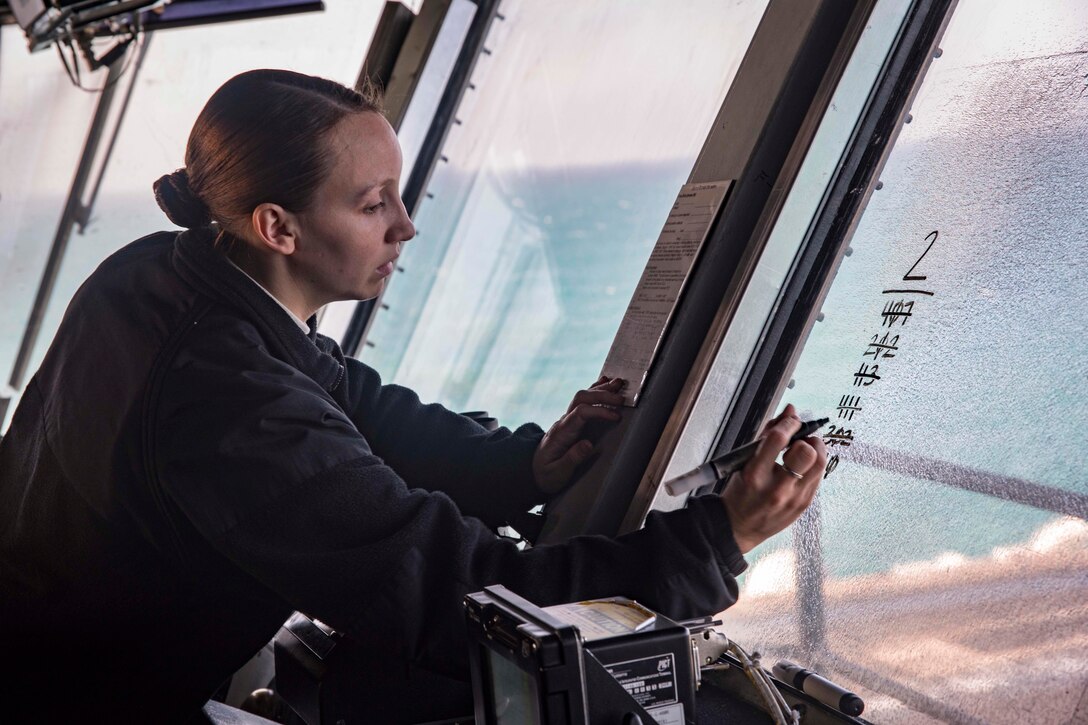 A sailor writes on the windshield of a boat.