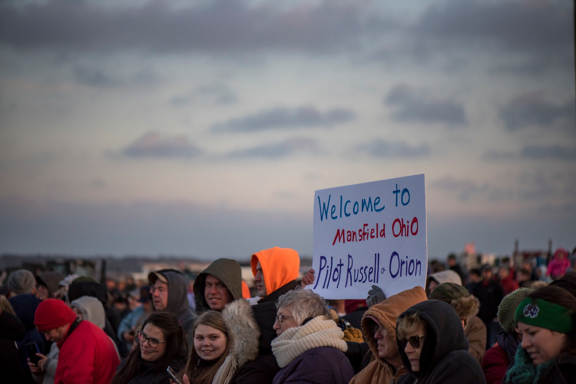 A photo of all the people who came to see the NASA Super Guppy at Mansfield Lahm Airport, holding up a sign that says Welcome to Mansfield Pilot Russell and Orion.