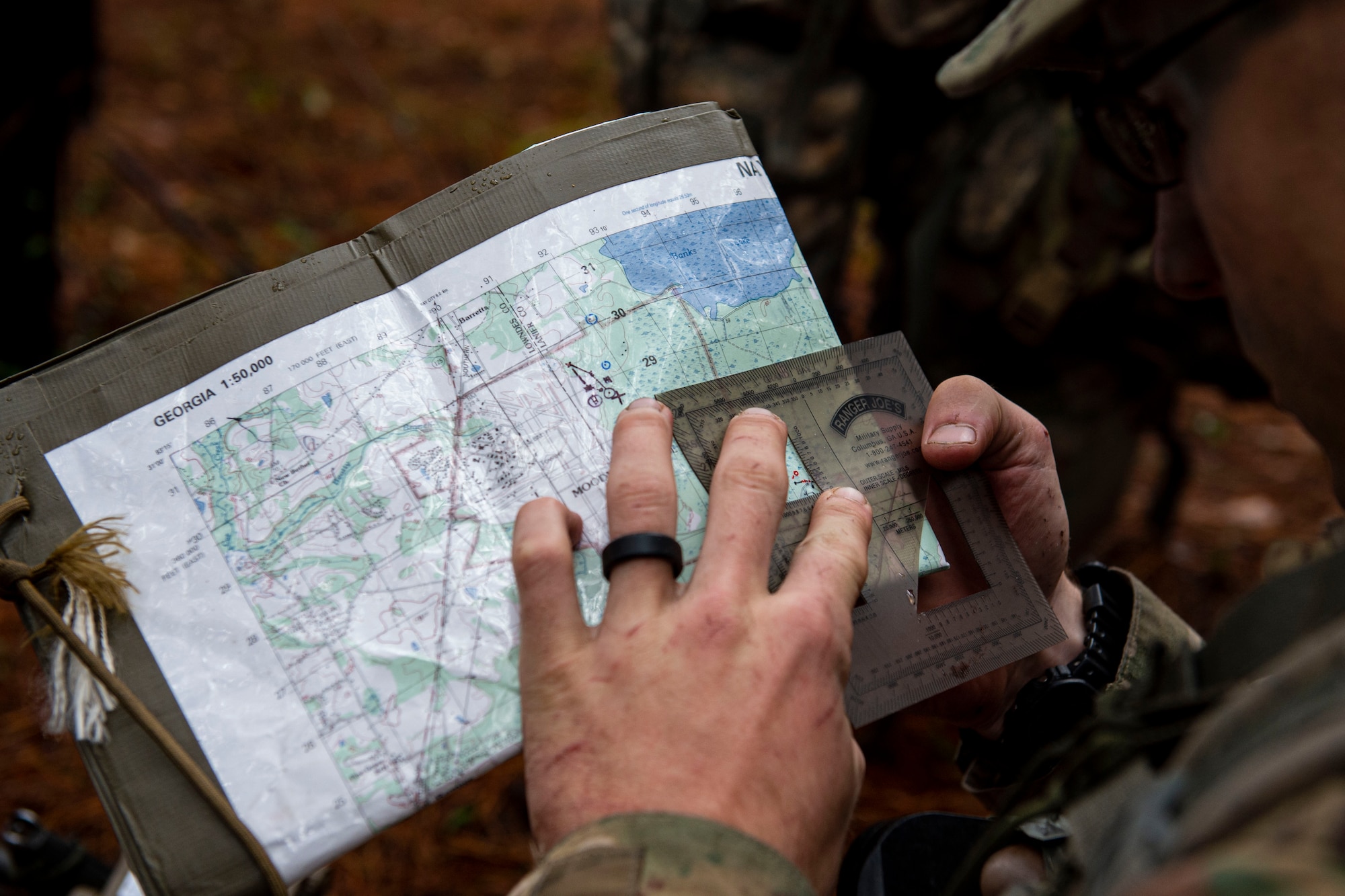 Airman 1st Class Dennis Hannas, an Air Force Ranger Assessment Course student, uses a protractor to pinpoint his location Nov. 15, 2019, at Moody Air Force Base, Ga. The course teaches students critical tasks such as land navigation, troop movements and shooting and maintaining weapons. Over the course of 19 days, the Ranger Assessment Course evaluates students to determine if they possess the knowledge, willpower and skill to attend Army Ranger School. (U.S. Air Force photo by Airman Azaria E. Foster)
