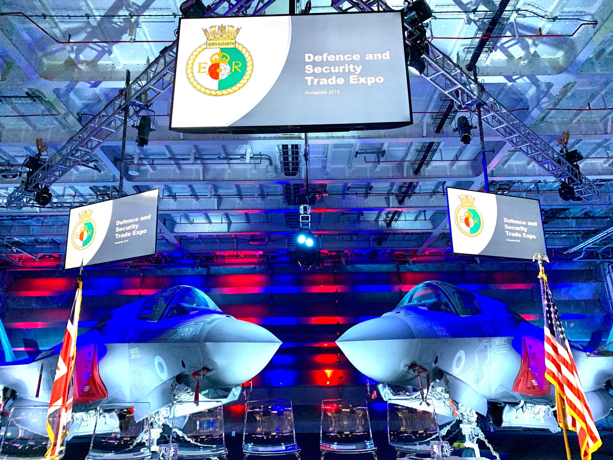Two F-35 Joint Strike Fighter fast jets provided a powerful backdrop on the stage inside the aircraft hangar on board the HMS Queen Elizabeth Nov. 20 when the two winning teams from the Swarm and Search AI Challenge: 2019 Fire Hack, were recognized. (Courtesy photo)