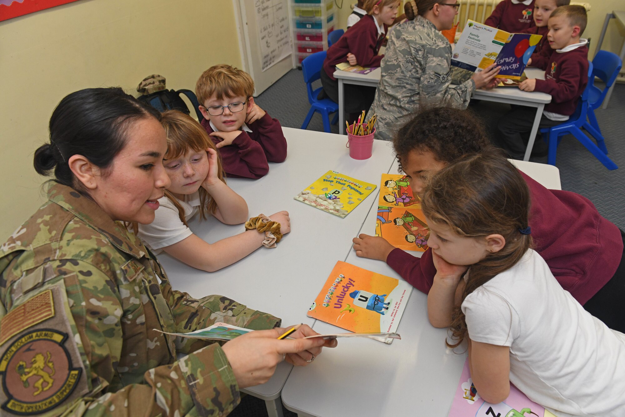 Airman 1st Class Janet Abilez, 100th Operations Support Squadron airfield management coordinator, reads a book to children at Houldsworth Valley Primary School in Newmarket, England, Nov. 26, 2019. Airmen from Team Mildenhall volunteered their time to go to the school to read books with the children and talk about their jobs on base. (U.S. Air Force photo by Senior Airman Luke Milano)