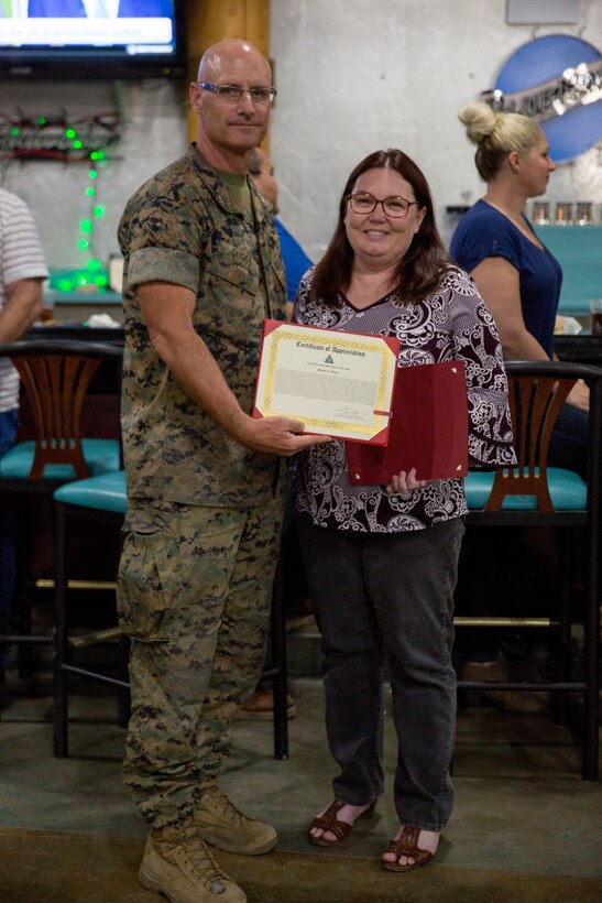 U.S. Marine Corps Col. David A. Suggs and Sgt. Maj. David M. Leikwood, the Commanding Officer and Sergeant Major of Marine Corps Air Station (MCAS) Yuma, present the Employee of the Year (EOY) Award to Ms. Sherri Utley, Oct. 24, 2019. Utley, previously selected as MCAS Yuma Employee of the Quarter, demonstrated she is the employee who shows the most work ethic, dedication, and the highest commitment throughout the entire year. (U.S. Marine Corps photo by Cpl Nicole Rogge)