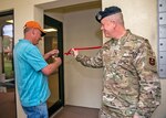 Ribbon cutting ceremony for new computer room at the Randolph dormitory. Dorm manager cuts a red ribbon with scissors as the 502nd Security Forces Group chief holds the ribbon steady.