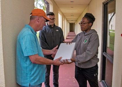Dormitory Manager, Joseph Turnbow,. 502nd Civil Engineers Squadron, hands the first package of printing paper to Airman 1st Class Amelia Franklin, dorm council president and commemorating the opening of the Airman Learning Center, Joint Base San Antonio-Randolph, Texas, November 22, 2019.