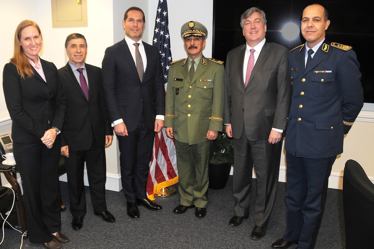 Civilian and military officials stand in a row for a photo.