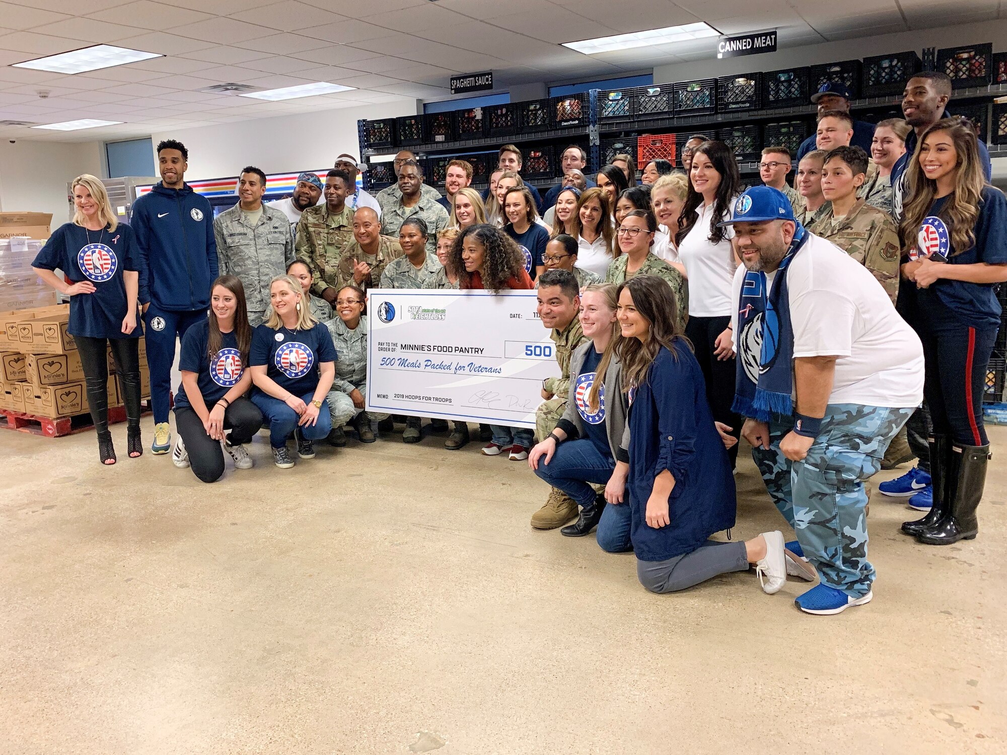 Team Fort Worth members pose with Dallas Mavericks players, team representatives and SOTA Weight loss volunteers as Minnie’s Food Pantry receives a "check" symbolizing the 500 meals that are being donated from the Dallas Mavericks, SOTA and the military to be used toward providing local veterans with food items and supplies. Hoops for Troops: Commitment to Service is a DoD annual initiative where the military and NBA teams from across the country partner together to serve their surrounding communities. (U.S. Air Force photo by Capt. Jessica Gross)