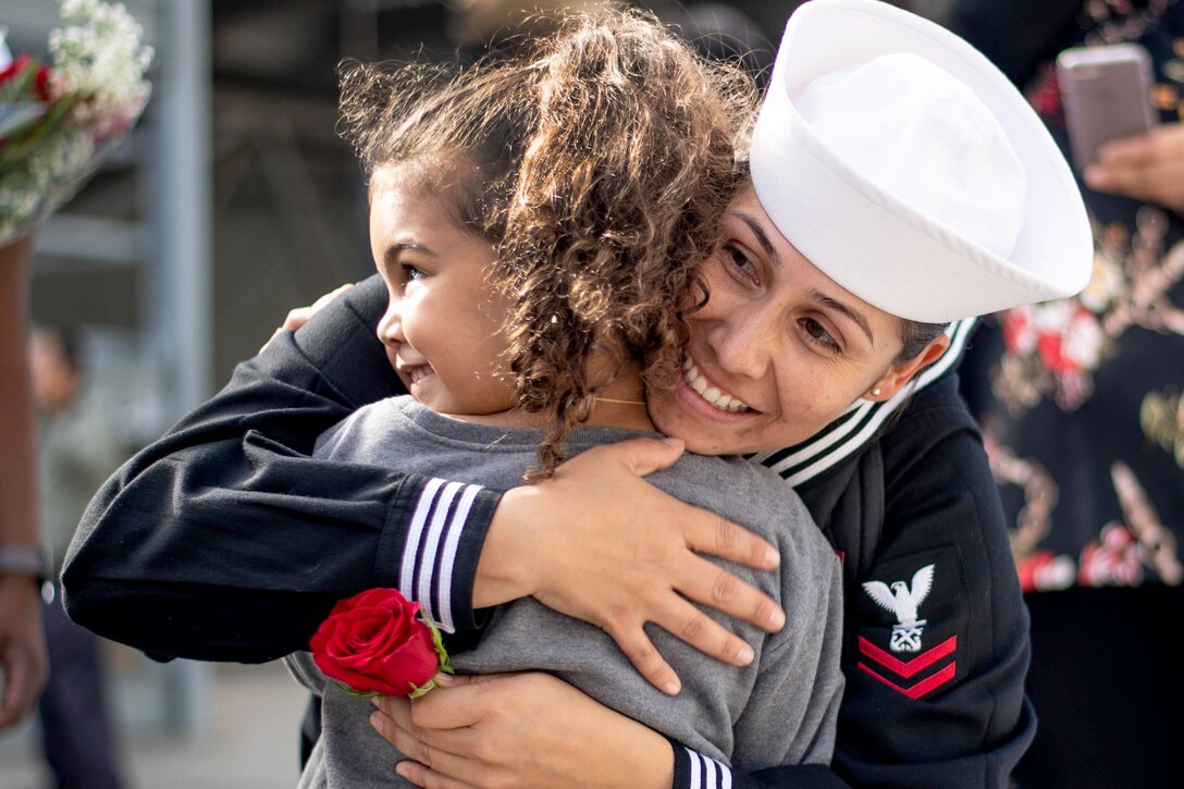 A female Navy officer embraces her child.