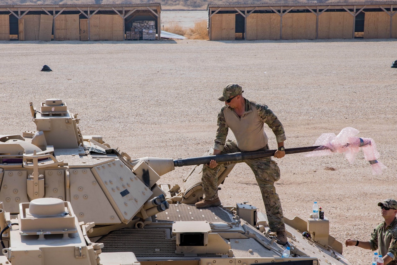 A soldier works on an armored vehicle.