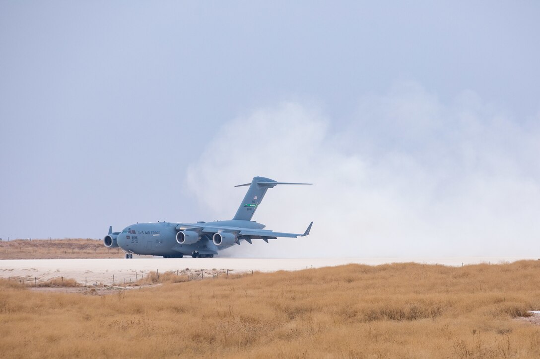 A jet lands on a dirt runway.