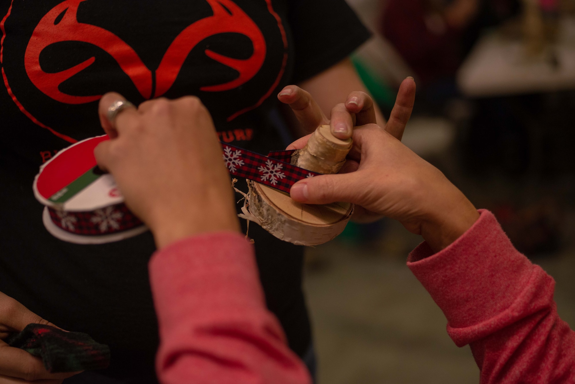 A 354th Logistics Readiness Squadron family member measures ribbon for a birch snowman hat at Eielson Air Force Base, Alaska, Nov. 7, 2019. Airmen and families of the 354th LRS gathered to build crafts and relationships during one of their monthly socials. (U.S. Air Force photo by Capt. Kay Nissen)