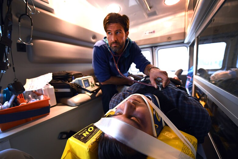 Kevin Mayorga, (left), Schriever Air Force Base paramedic, monitors his simulated patient in an ambulance transport during exercise Opinicus Vista 19-3, Nov. 19, 2019.