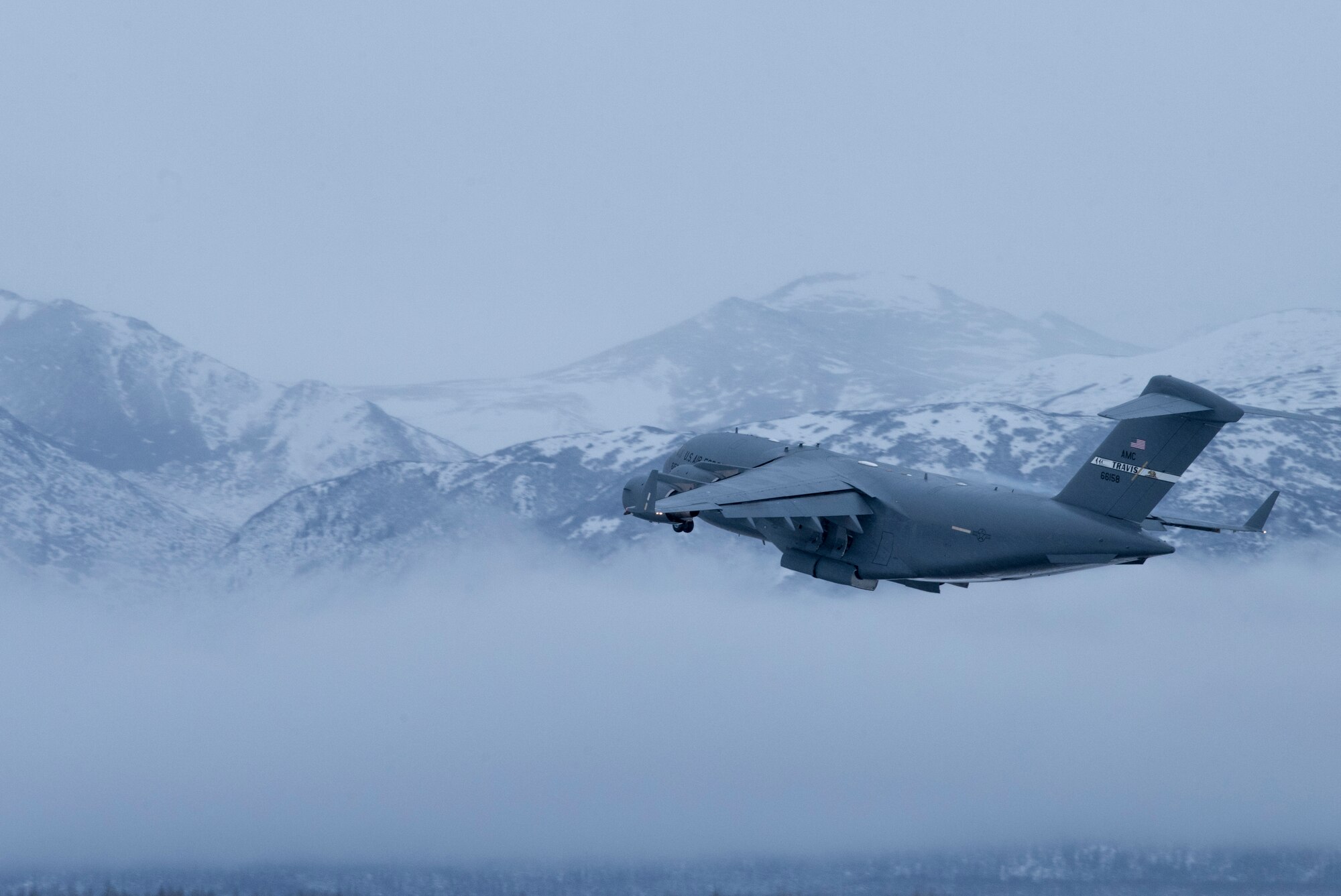 A U.S. Air Force C-17 Globemaster III assigned to Travis Air Force Base, Calif., flies over the Chugach Mountains during cold weather aircraft maintenance procedures training at Joint Base Elmendorf-Richardson, Alaska, Nov. 19, 2019. The training prepared Airmen to operate in arctic environments.