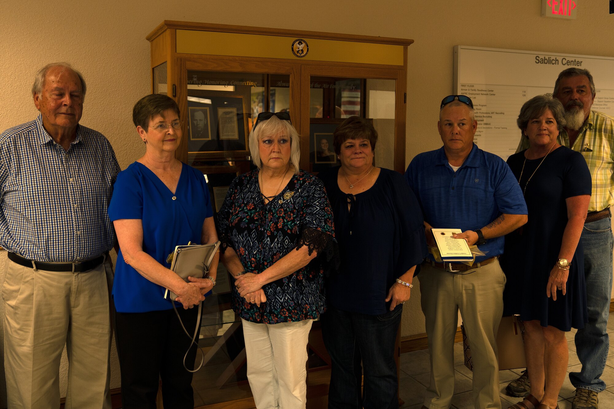 Gold Star families pose for a photo in front of the Fallen Heroes Cabinet display in the Sablich Center at Keesler Air Force Base, Mississippi, Sept. 30, 2019. The display was dedicated to Gold Star families to maintain the memory of fallen heroes and let the families know they are not forgotten. (U.S. Air Force photo by Airman 1st Class Kimberly Mueller)