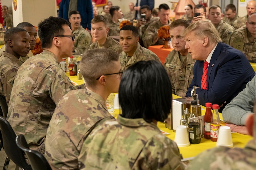 President Donald J. Trump speaks with service members  while they eat.