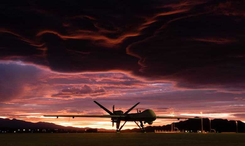 An MQ-9 Reaper sits on the flight line as the sun sets