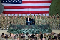 A man speaks from behind a podium  surrounded by military members.