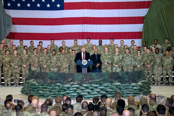 A man speaks from behind a podium  surrounded by military members.