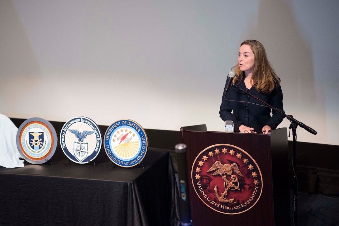 Woman speaks into a microphone at a lecturn.