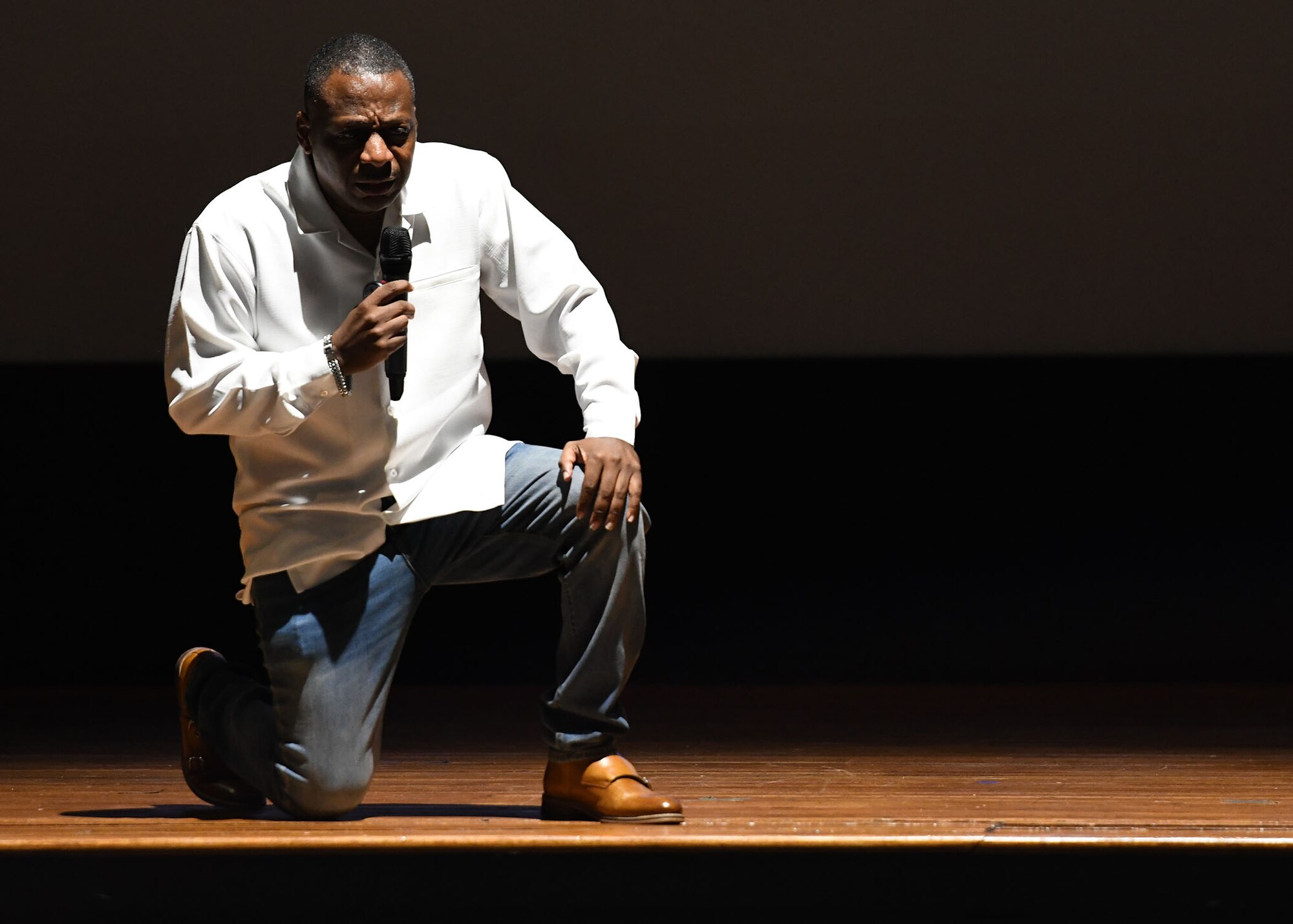 A man stands on a stage and speaks to Airmen.