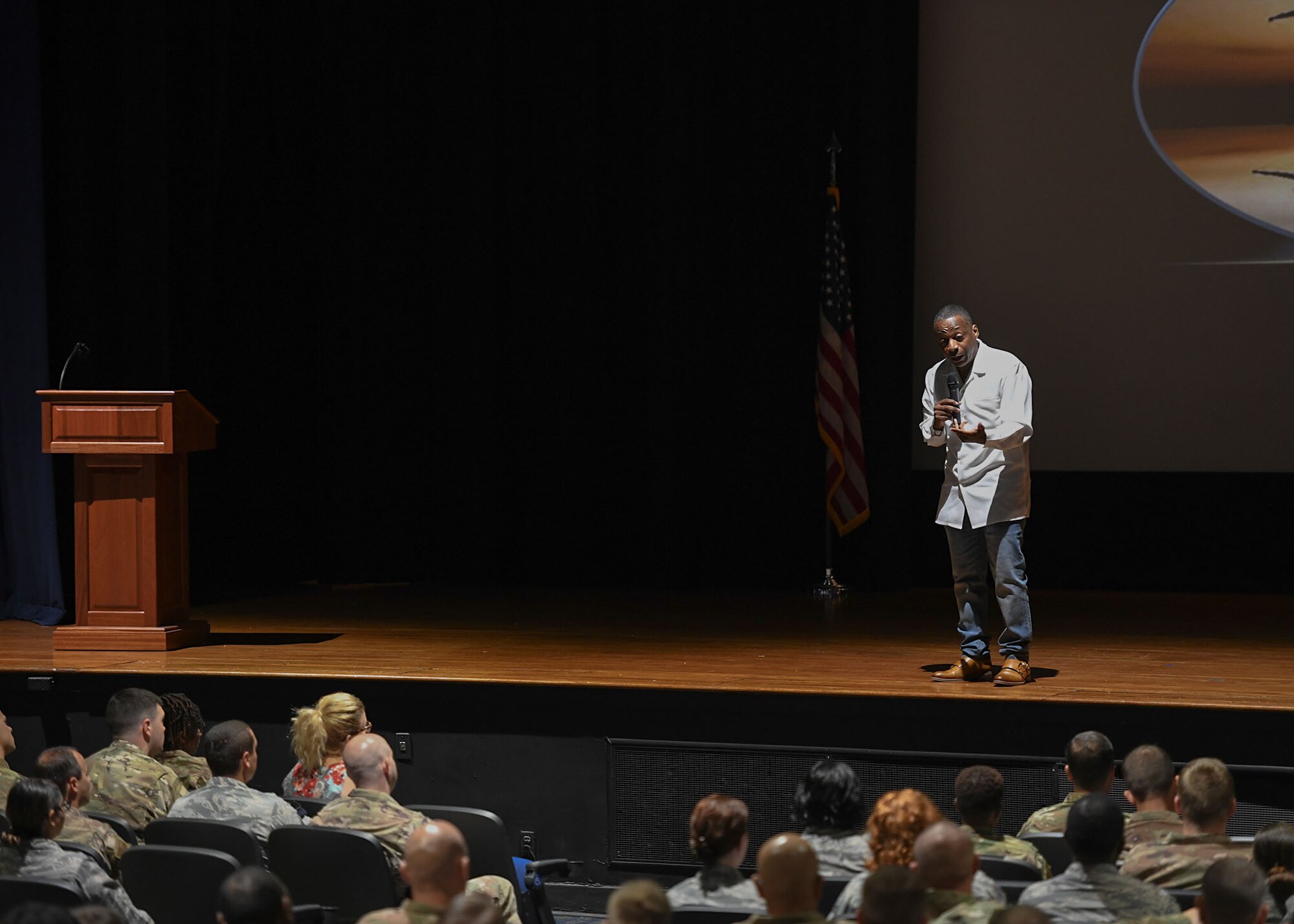 A man stands on a stage and speaks to Airmen.