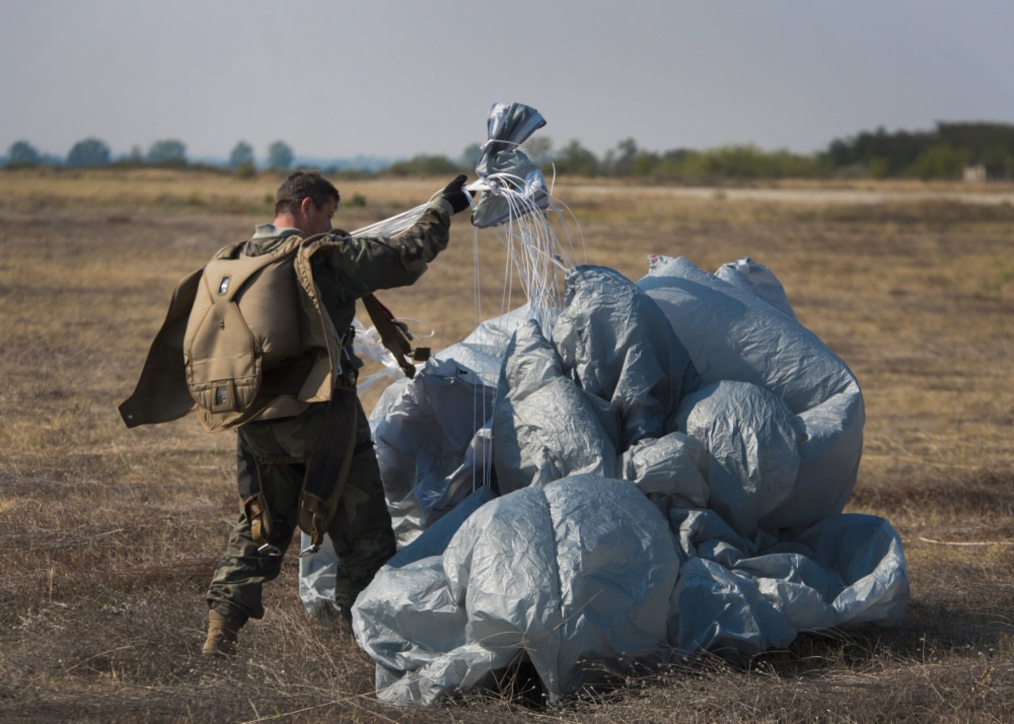 A jumper with Bulgaria’s 68th Special Forces Brigade recovers his parachute after a jump into Cheshnegirovo drop zone in Plovdiv, Bulgaria, Sept. 26, 2019. Once the students of the military free-fall course landed, they were expected to recover their parachutes and prepare to jump again. (U.S. Air Force photo by Staff Sgt. Kirsten Brandes)