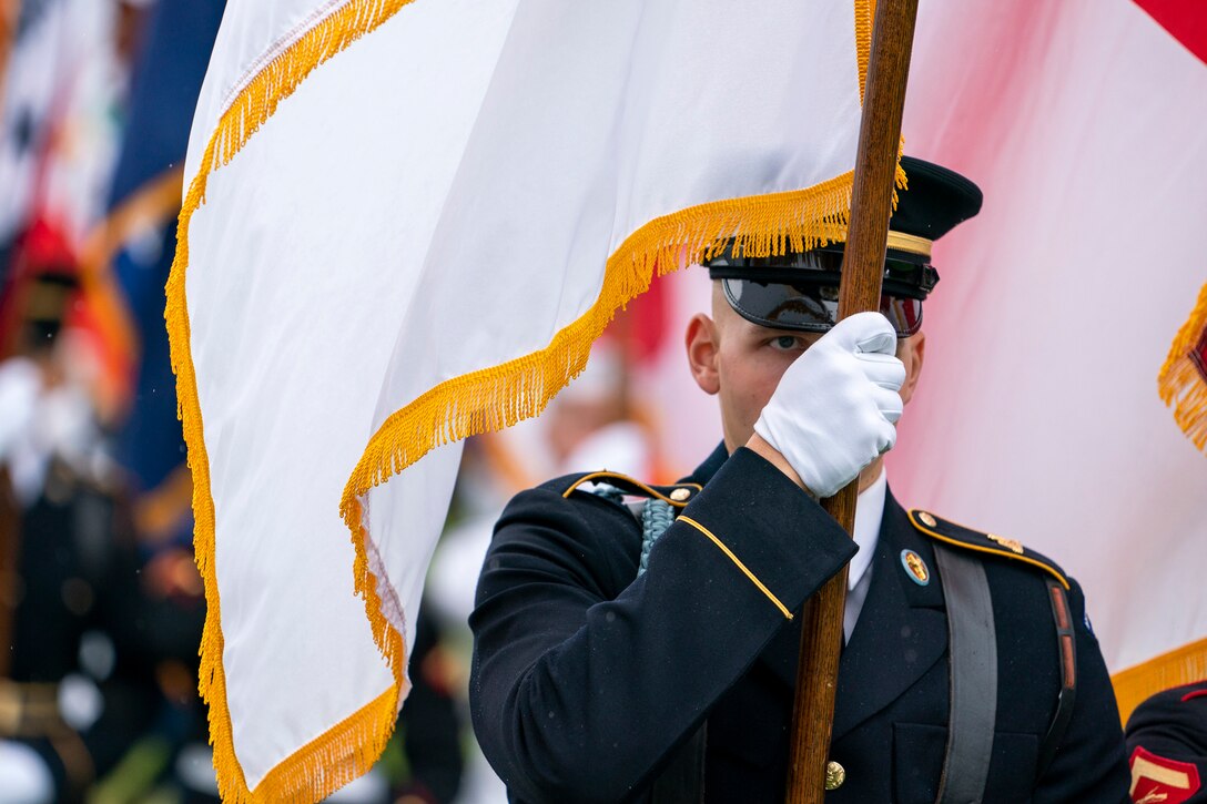A service member carries a flag during a ceremony.