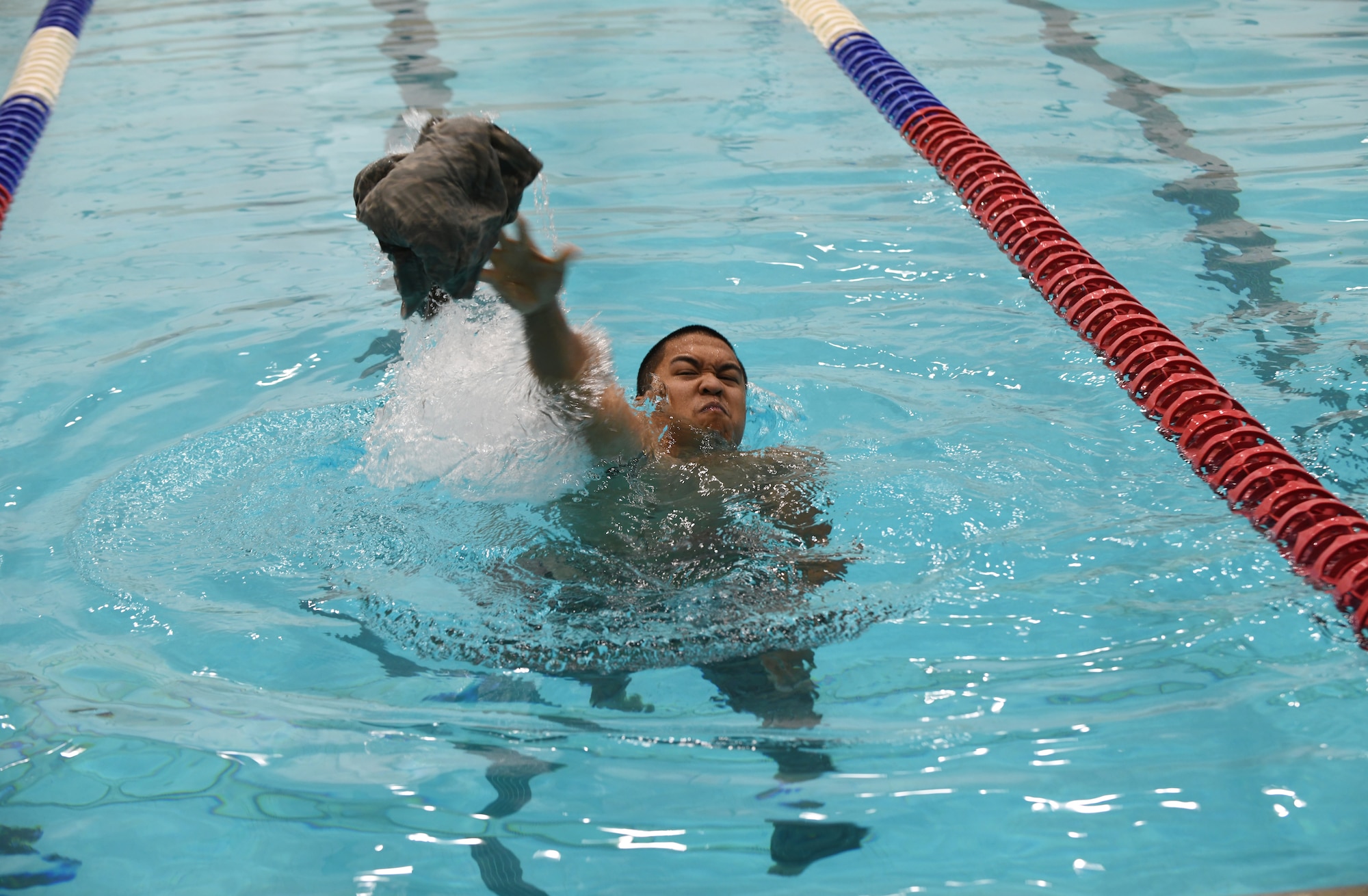 Staff Sgt. Jefferey Sales, a 28th Security Forces Squadron combat arms instructor, throws his top onto the pool deck at the Bellamy Fitness Center on Ellsworth Air Force Base, S.D., Sept. 20, 2019. Participants of the German Armed Forces Proficiency Test swam 100 meters in uniform, then undressed while treading water. The event was completed once participants successfully landed their uniforms onto the pool deck. (U.S. Air Force photo by Airman 1st Class Christina Bennett)