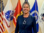 Photo of female in blue business suit standing in front of flags