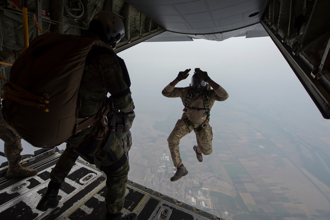 An airman jumps out of a military aircraft.