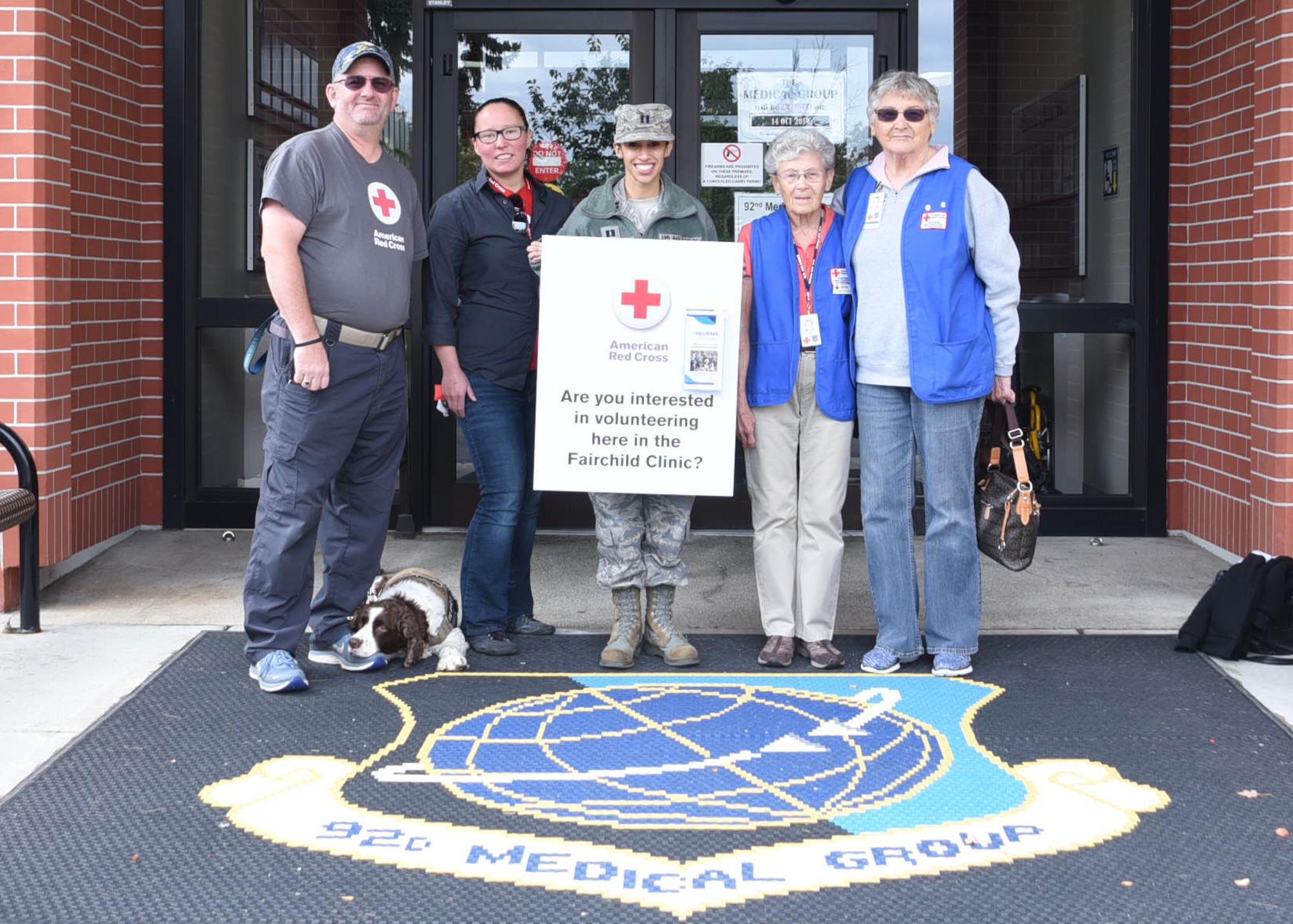 Members from the American Red Cross volunteer program and Capt. Aurora Seefong, 92nd Medical Group Education and Training flight officer, pose in front of Team Fairchild’s 92nd MDG.