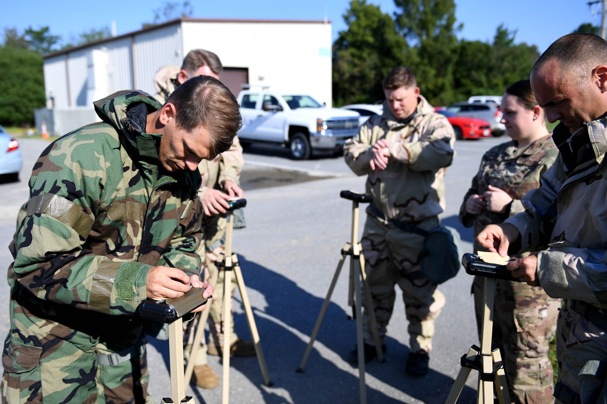 People in CBRN gear look at paper.