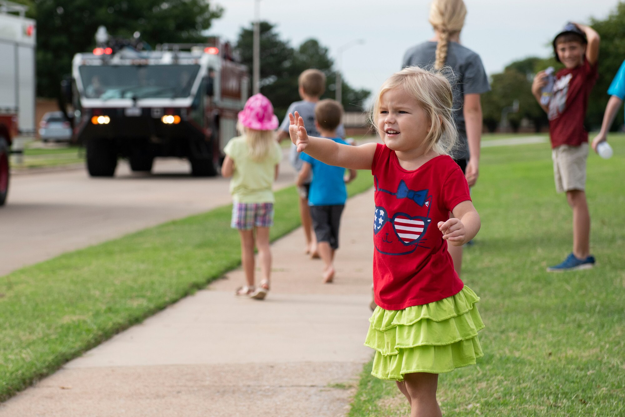 Military children watch the a fire deparptment parade through base housing.