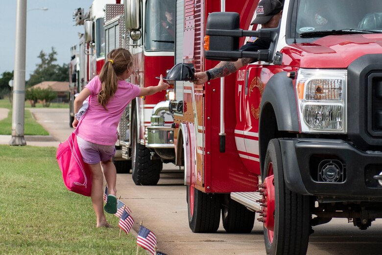 Military children watch the a fire deparptment parade through base housing.
