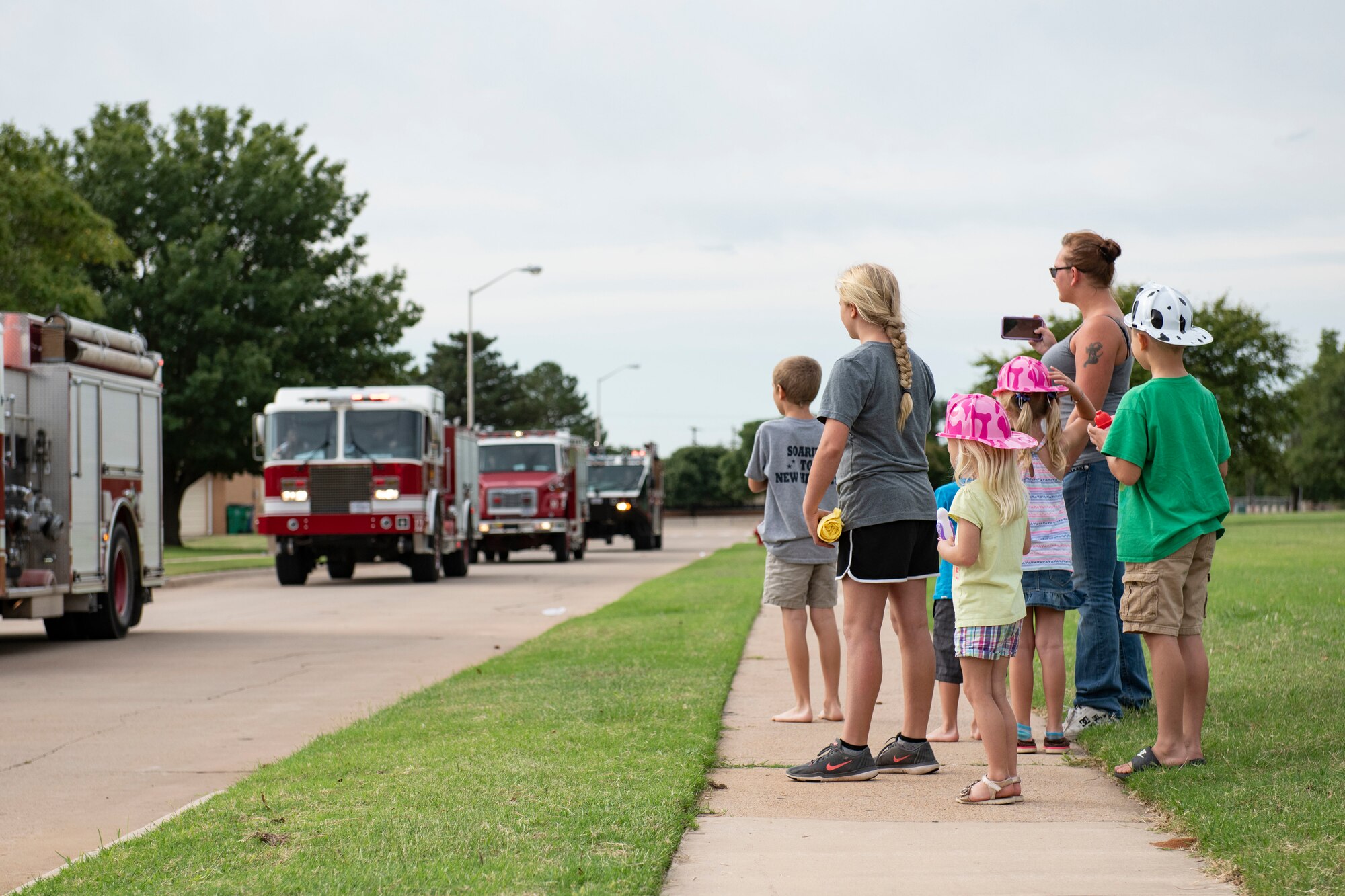 Military children watch the a fire deparptment parade through base housing.
