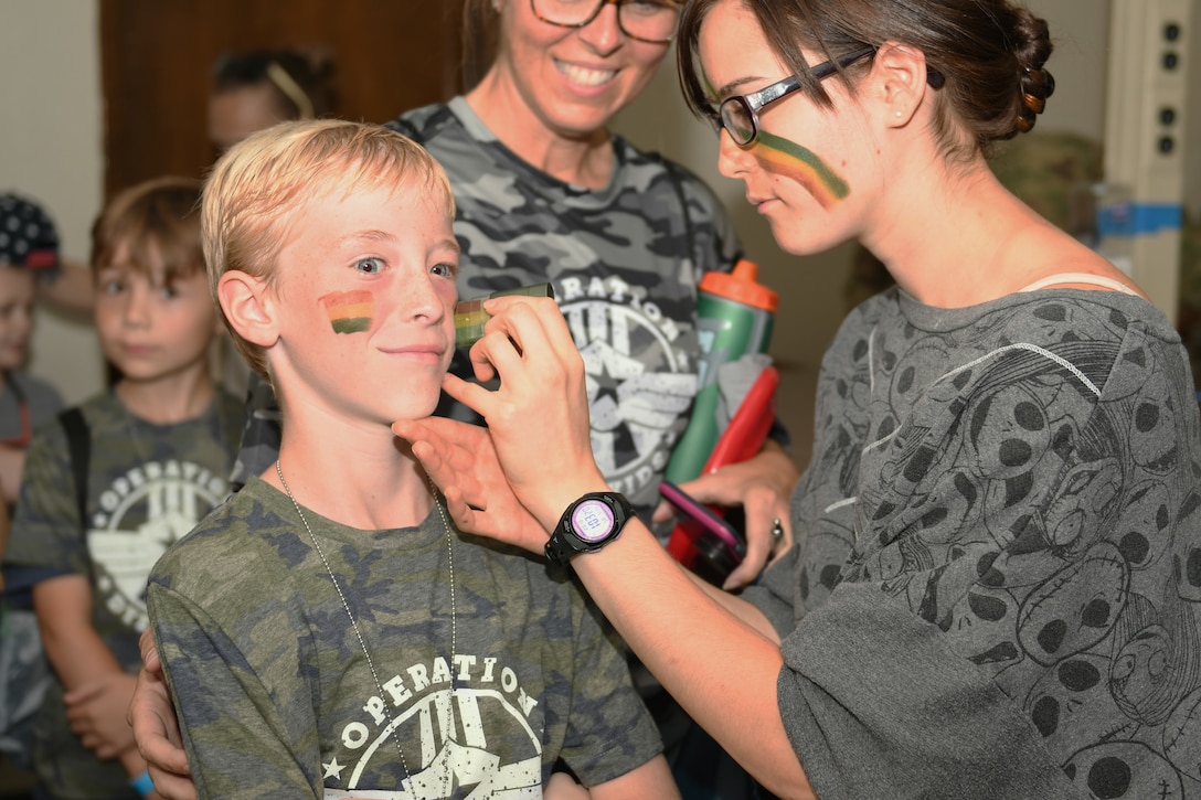 Peyton Hammond, son of Senior Master Sgt. Julie Hammond, 7th Force Support Squadron career assistance advisor, receives face paint from Candice Kissam, daughter of Master Sgt. Chris Kissam, 7th Bomb Wing religious affairs superintendent, during Operation Dyess Kids at Dyess Air Force Base, Texas, Sept. 28, 2019.