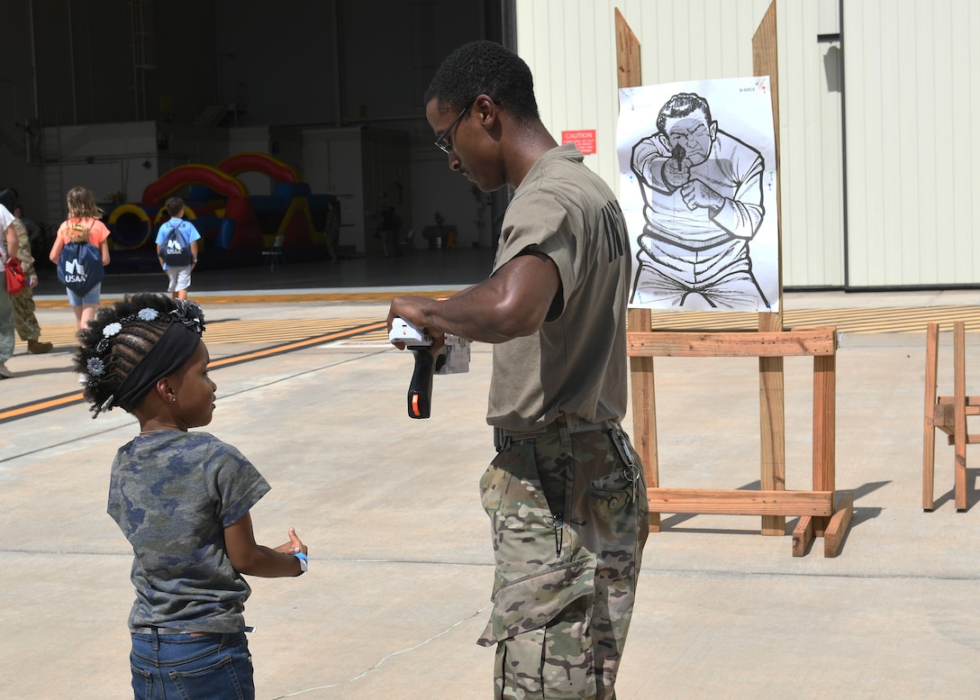 Staff Sgt. Jalen Snyder, 7th Security Forces Squadron combat arms instructor, reloads a toy gun for Sapphire Johnson, daughter of Tech. Sgt. Rebecca Johnson, 489th Bomb Group command support staff NCO in charge, during Operation Dyess Kids at Dyess Air Force Base, Texas, Sept. 28, 2019.
