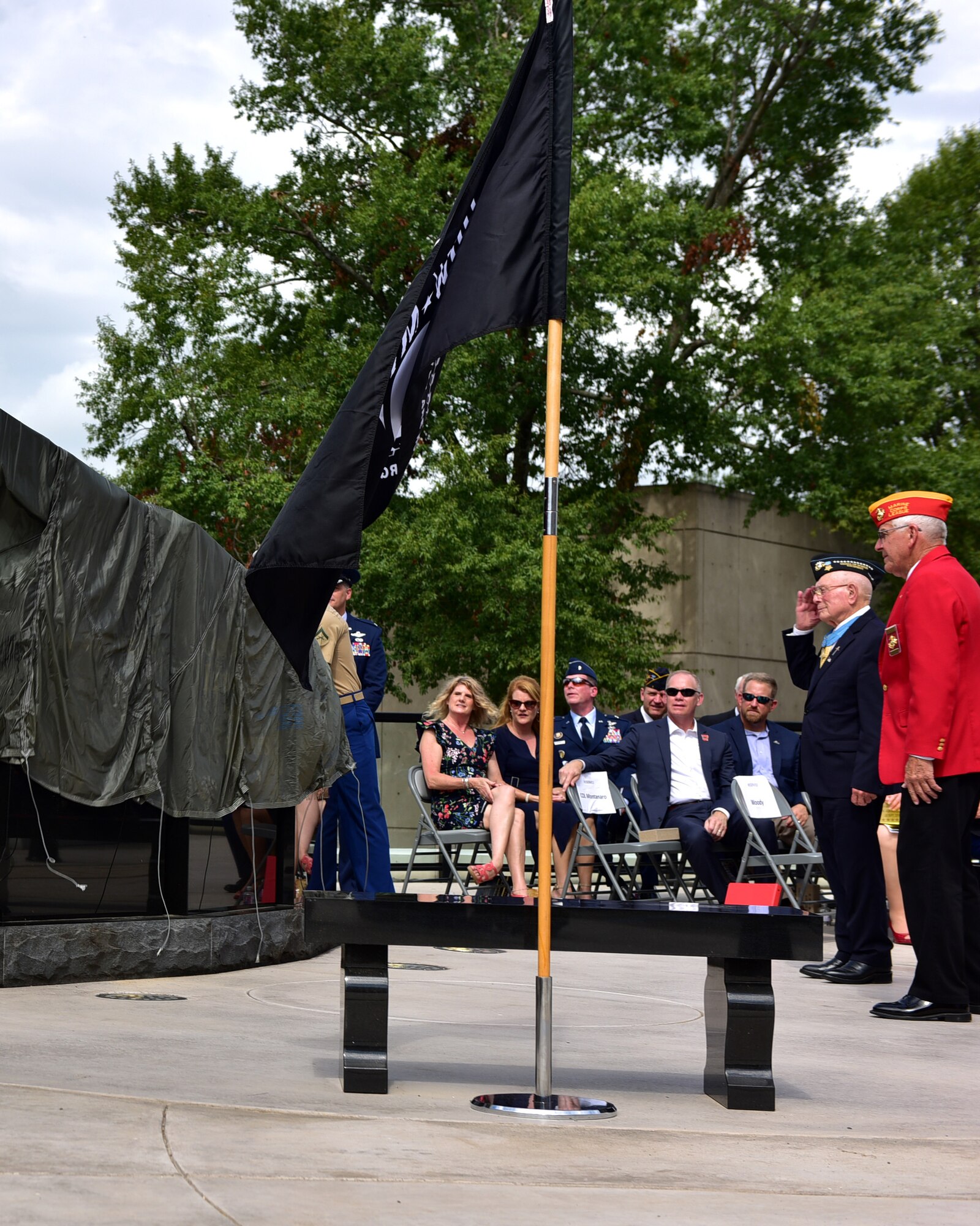 Individuals gather in an outdoor court yard to see a black monument