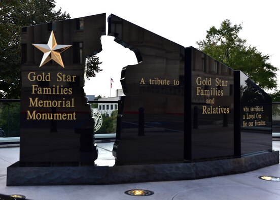 Individuals gather in an outdoor court yard to see a black monument