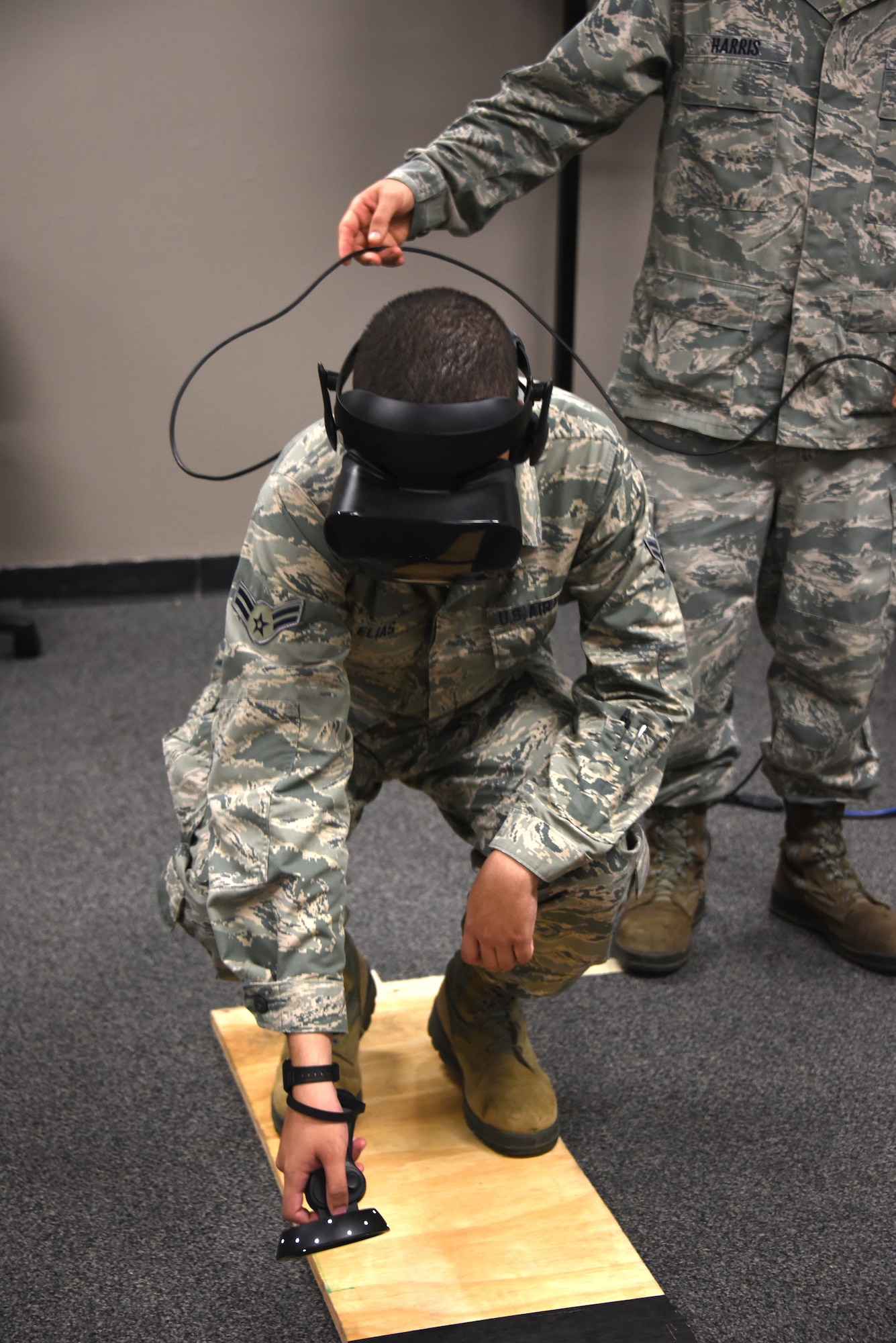 366th Training Squadron electrical systems apprentice course student, reaches to the ground during a virtual reality fear of heights assessment